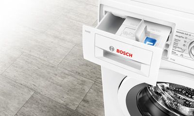 Helle Küche mit Holzfußboden, Tisch und eingebaute Geräte.